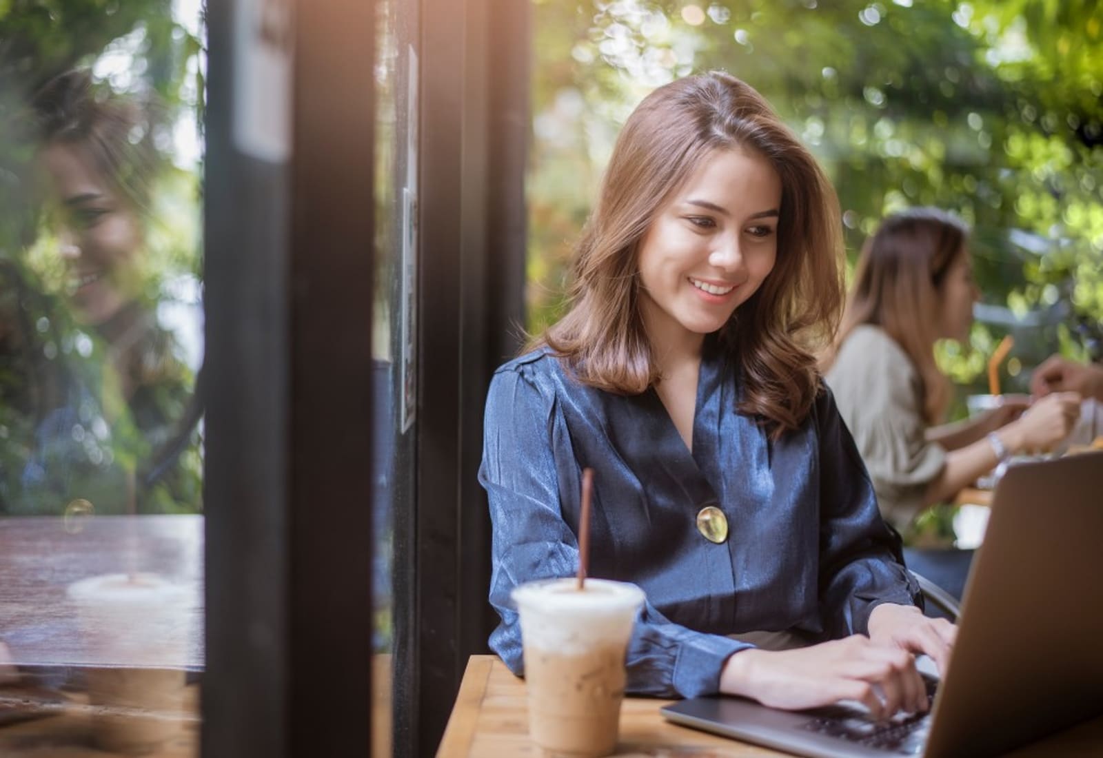 Studentin schreibt ihre Masterarbeit am Laptop am Fensterplatz