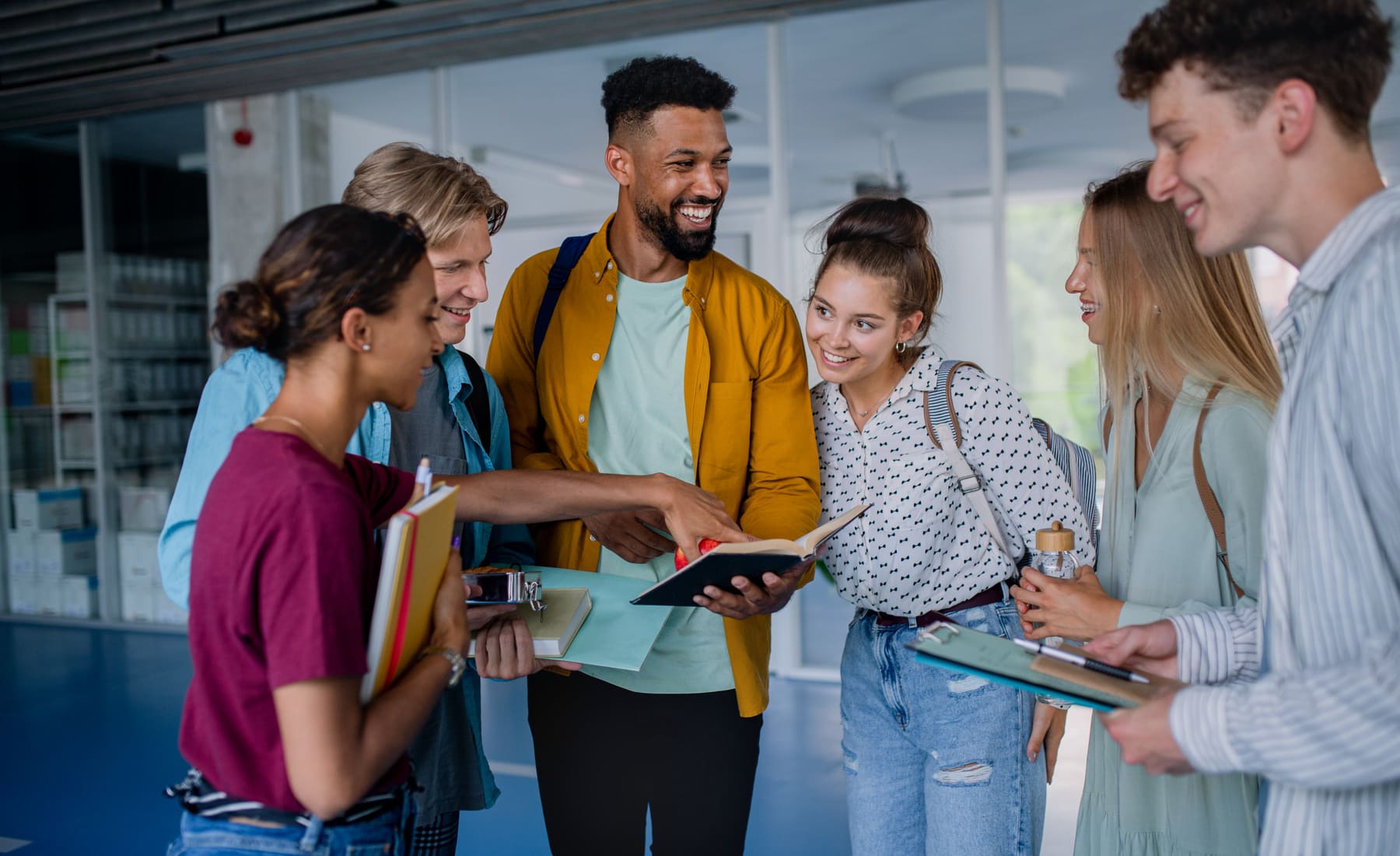 Gruppe von Studierenden im Universitätsgebäude tauscht sich über Unterlagen aus